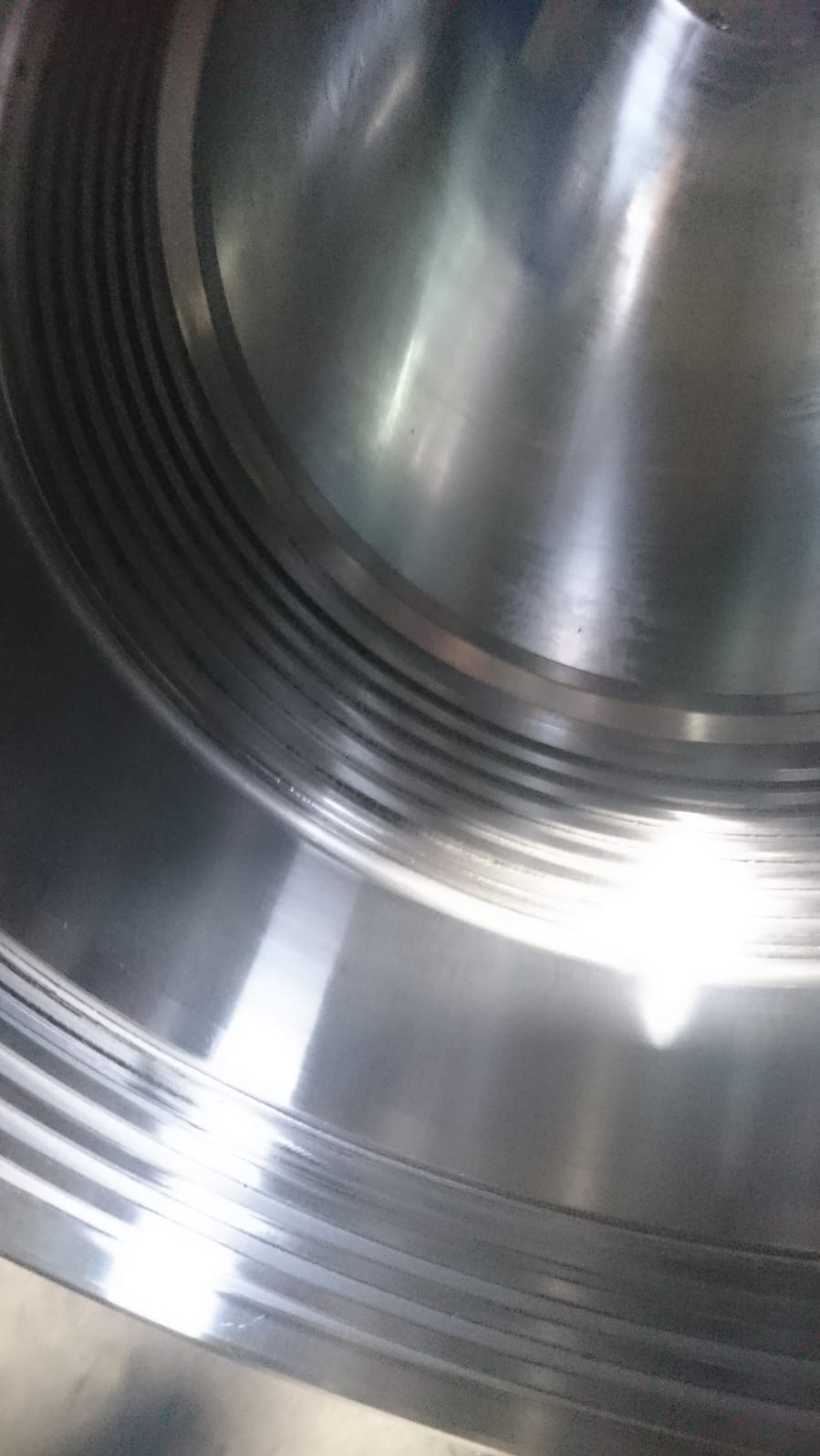 Wnętrze metalowego elementu z widocznymi, precyzyjnie wykonanymi rowkami, oświetlone punktowo, dające efekt lustrzanego odbicia.