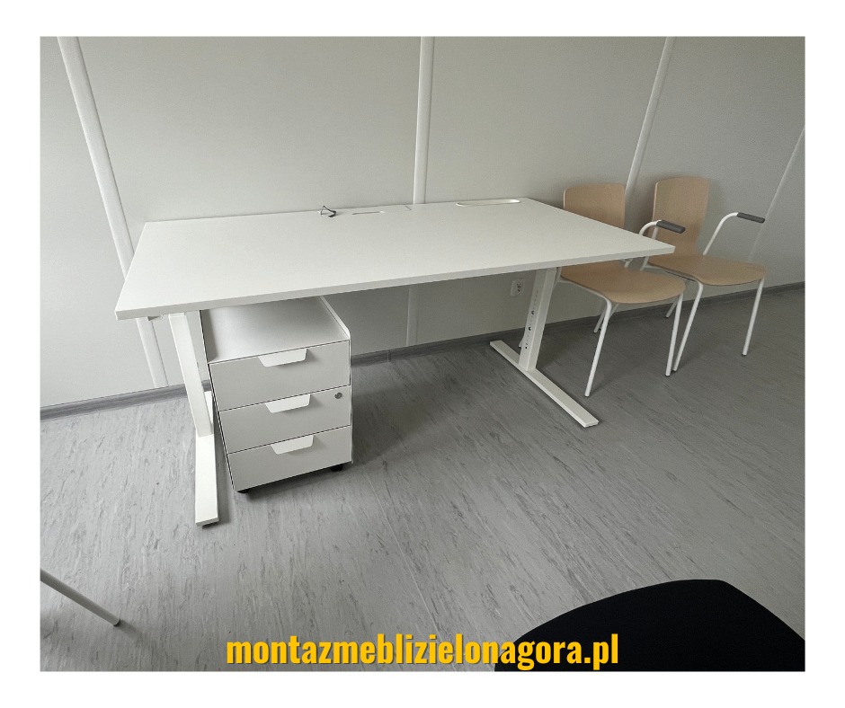 Białe biurko z regulowaną wysokością, trzema szufladami i dwoma krzesłami w tle, ustawione w minimalistycznym biurze z panelami ściennymi.