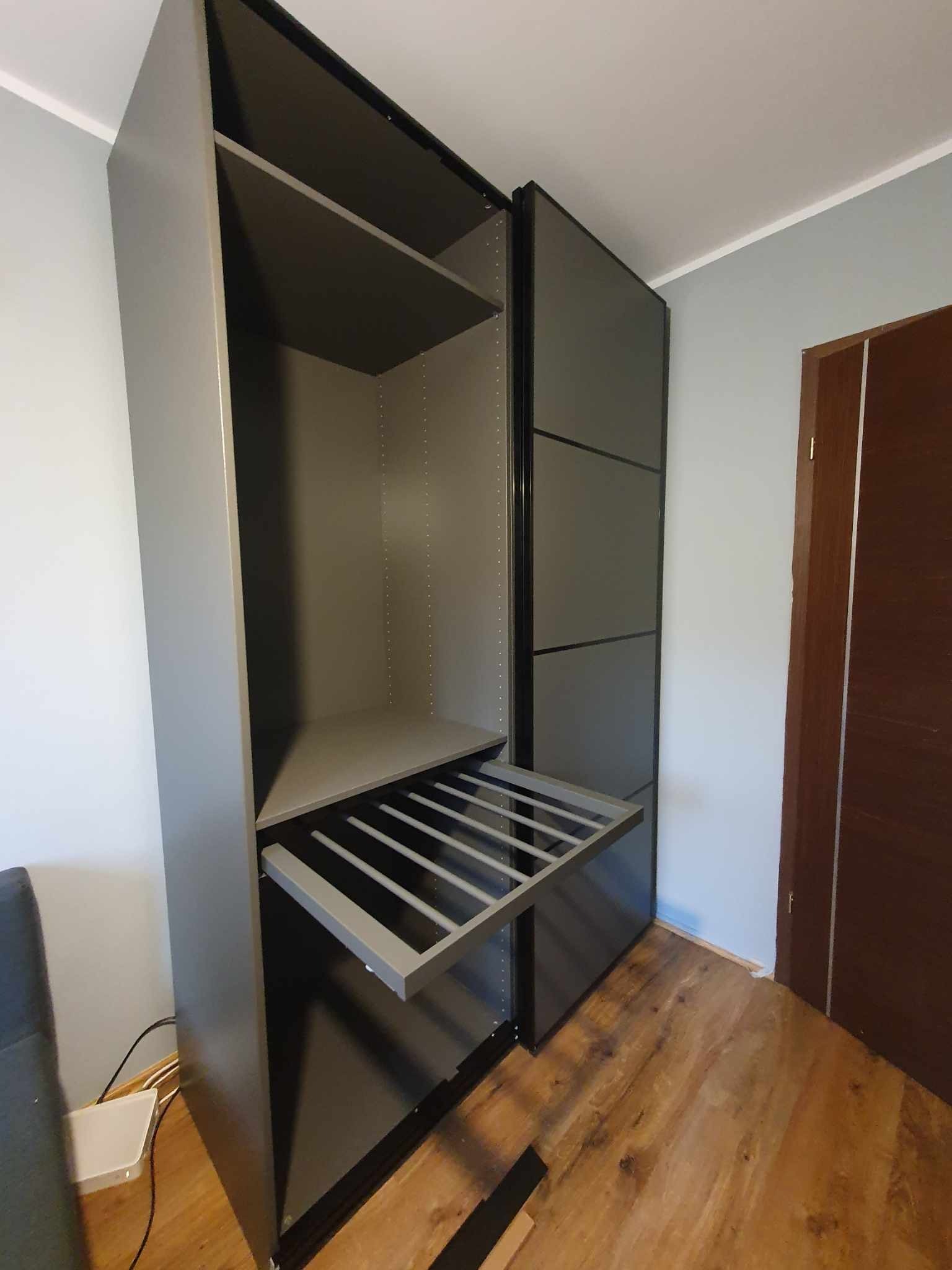 Szara szafa wnękowa z wysuwanym wieszakiem na spodnie, widok z boku na drewnianej podłodze.