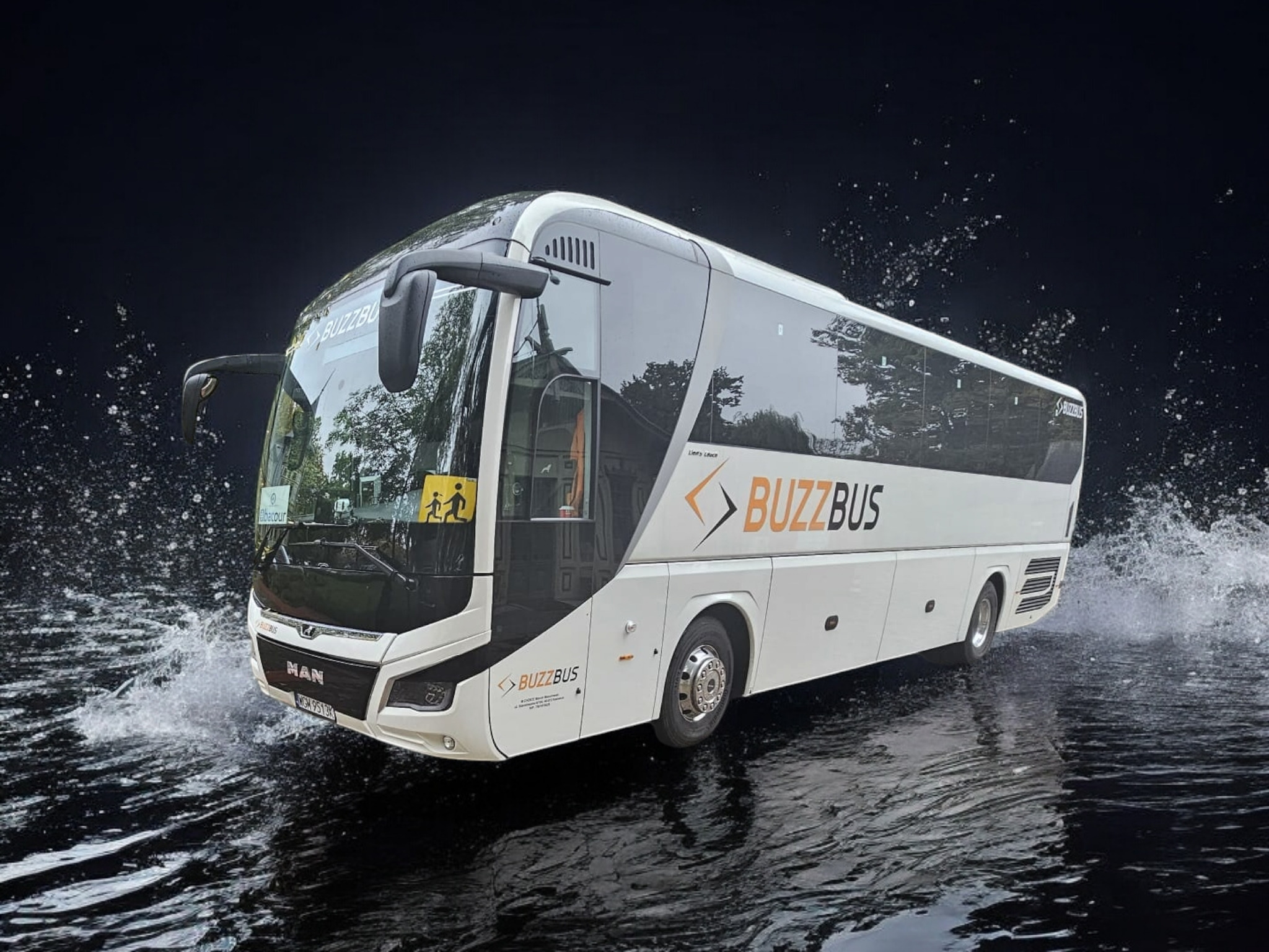Nowoczesny, biały autobus marki MAN z logo BuzzBus, dynamicznie pokonujący kałużę, z widocznym znakiem informującym o przewozie dzieci.