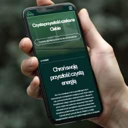 Upsitestudio Sp.z o.o. - Prezentacja strony internetowej na smartfonie, ukazująca zielony interfejs z hasłem 'Czysta przyszłość czekana Ciebie' i informacjami o Eko-Dom Instalacje, firmie specjalizującej się w nowoczesnych...