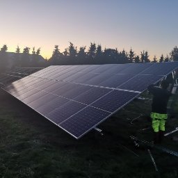 POLSKA GRUPA SPRZEDAŻY SPÓŁKA Z OGRANICZONĄ ODPOWIEDZIALNOŚCIĄ - Montaż paneli na konstrukcji wsporczej przez dwóch instalatorów na tle zachodzącego słońca.