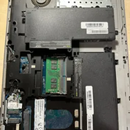 Wnętrze laptopa HP z widocznymi komponentami: baterią, wentylatorem, modułami pamięci RAM i dyskiem SSD. Widoczne oznaczenia i numery seryjne podzespołów.