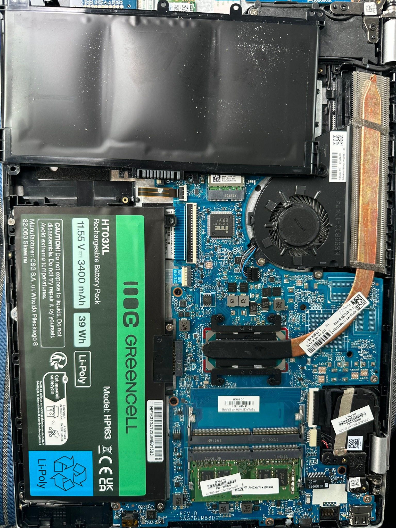 Wnętrze otwartego laptopa z widoczną baterią GreenCell, płytą główną i elementami chłodzenia. Szczegółowy widok na podzespoły komputera.