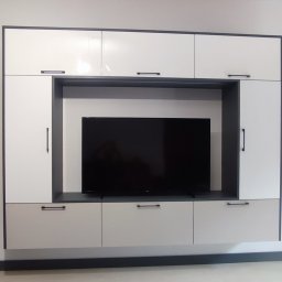 Piotr Andrukh - Nowoczesna zabudowa ściany telewizyjnej z białymi i szarymi frontami szafek, minimalistyczne uchwyty.