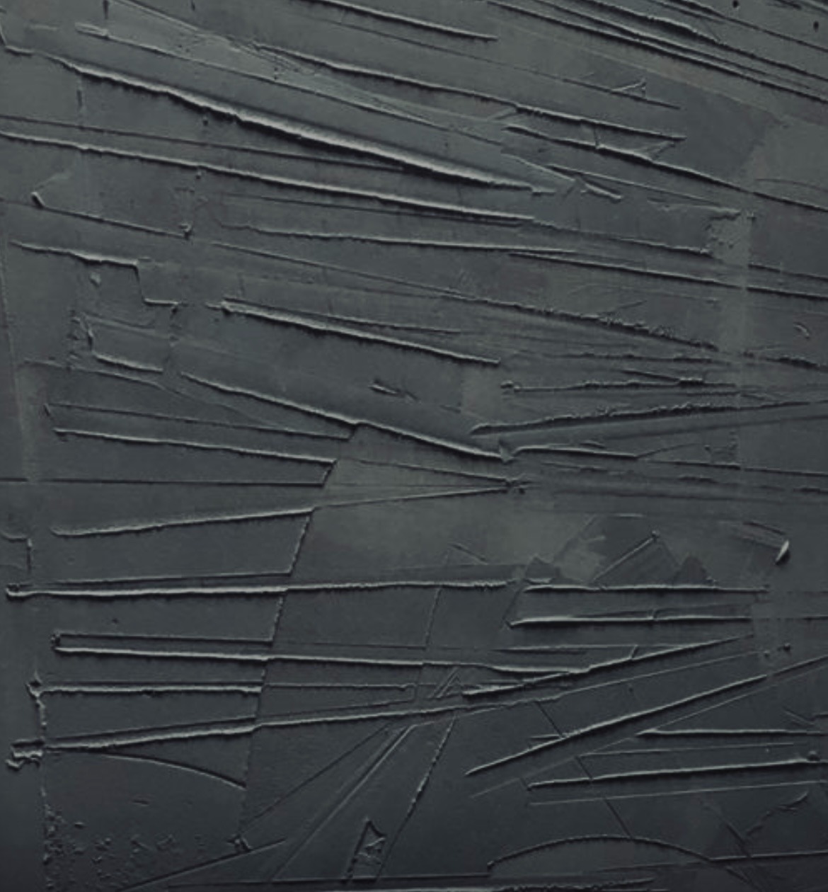 Szara ściana z fakturą nałożoną szpachelką w geometryczne wzory.