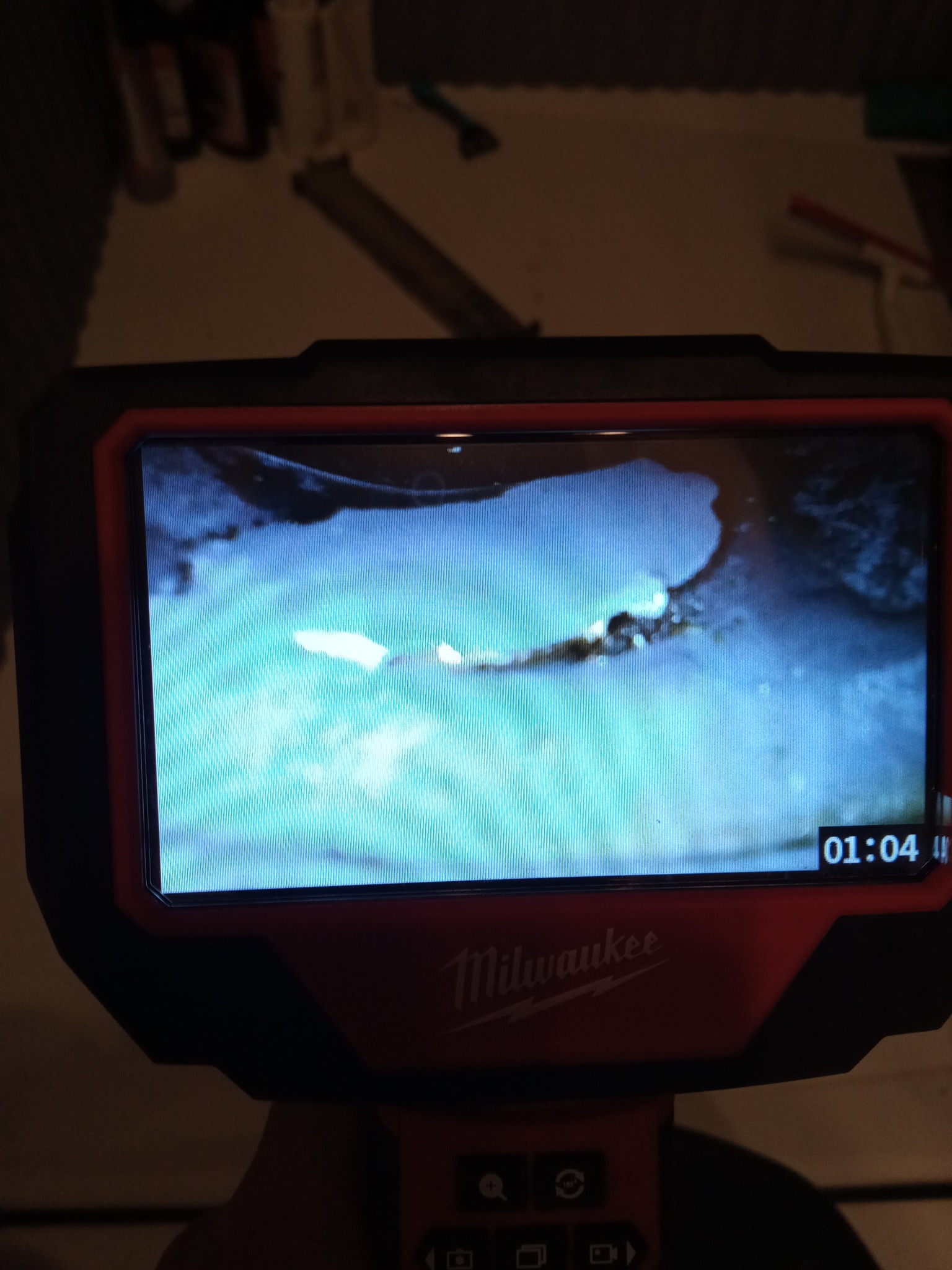 Ekran kamery inspekcyjnej marki Milwaukee wyświetla obraz z wnętrza rury, widoczny osad i zanieczyszczenia, na ekranie widoczny czas nagrania.