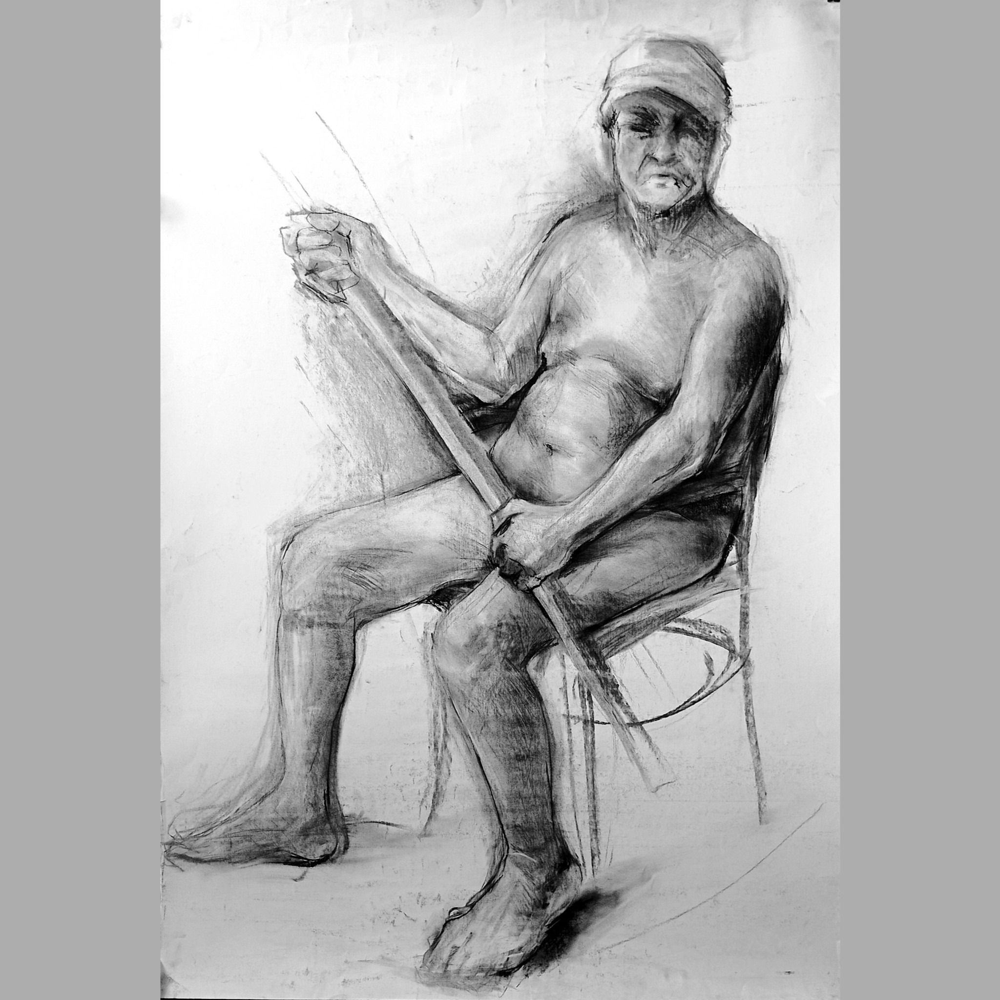 Szkic ołówkiem przedstawiający siedzącego mężczyznę z bandażem na głowie, trzymającego w dłoniach prostokątny przedmiot.