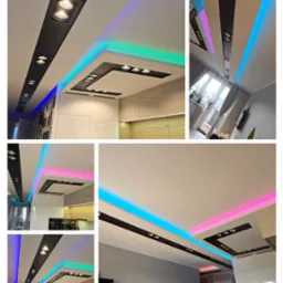 Nowoczesne oświetlenie sufitowe LED w kuchni, z podświetleniem RGB, tworzące unikalny klimat. Czarny panel z reflektorami, biały sufit, minimalistyczny design.