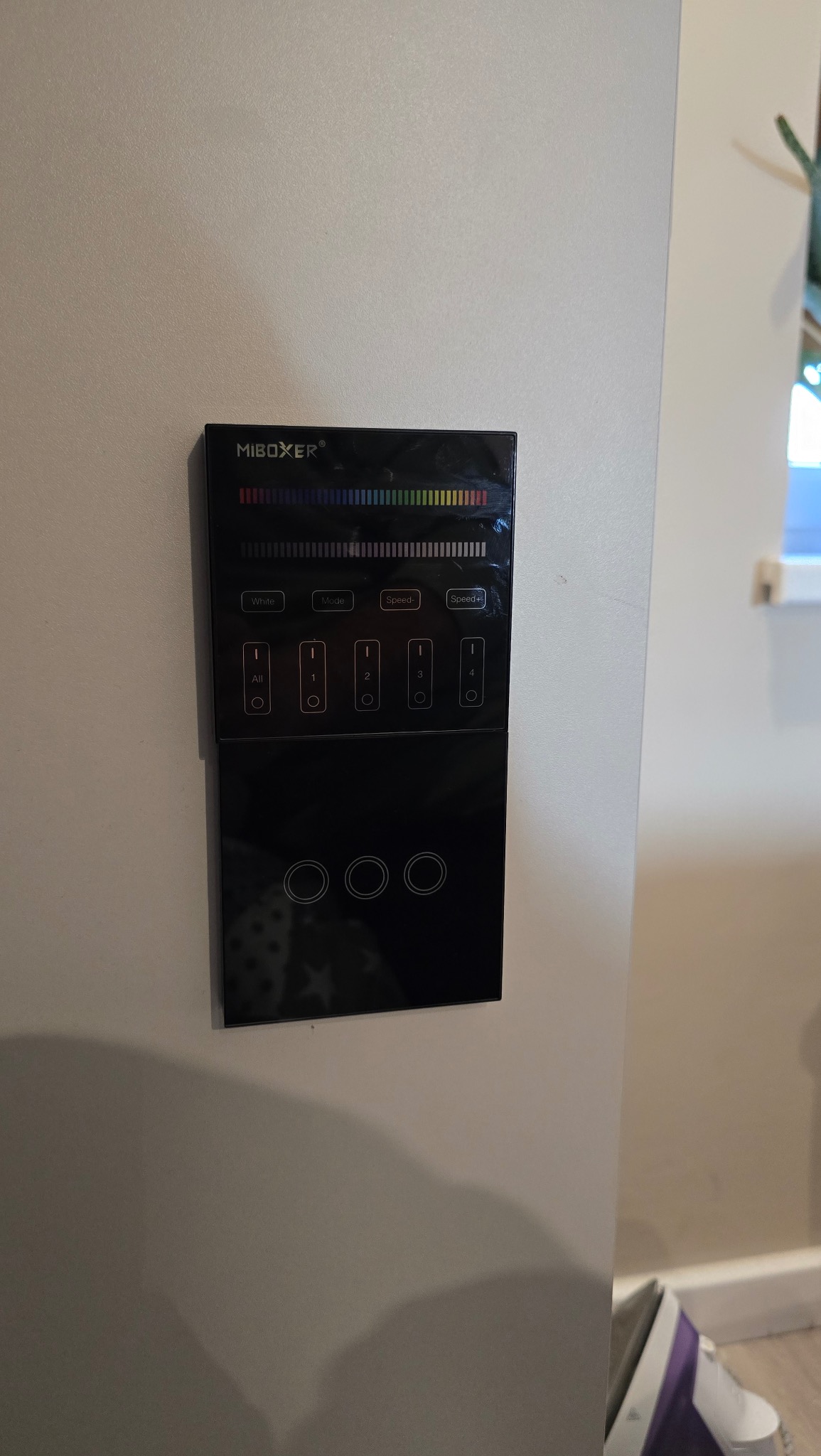 Czarny, dotykowy panel sterowania oświetleniem LED firmy Miboxer, zamontowany na białej ścianie, z widocznymi przyciskami funkcyjnymi i diodami LED.