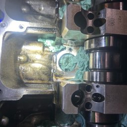 MOBILNA MECHANIKA MICHAŁ GRUDZIEŃ - Wnętrze głowicy silnika z wałkiem rozrządu, widoczne ślady oleju i fragmenty papieru zabezpieczającego.