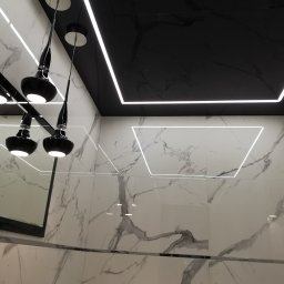 Build in Trust - Nowoczesna łazienka z czarnym sufitem podwieszanym z oświetleniem LED, marmurowe płytki ścienne i designerskie lampy wiszące z czarnymi kloszami.