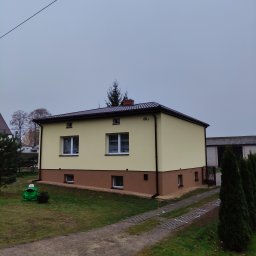 Renova Lublin - Dwukondygnacyjny budynek z ocieploną elewacją w kolorze kremowym i brązowym, z widocznym numerem 60A, sfotografowany w pochmurny dzień z perspektywy trawnika, gdzie stoi zielona plastikowa żaba.