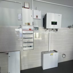 GLOBCORE - Zamontowany inwerter hybrydowy Sofar Solar połączony z magazynem energii Sofar Solar, widoczna rozdzielnica elektryczna i okablowanie na ścianie z jasnych płytek ceramicznych.