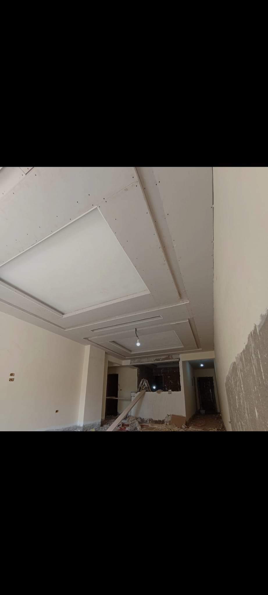 Montaż sufitu podwieszanego z płyt karton gips w trakcie remontu mieszkania, widoczne łączenia płyt i częściowo wyszpachlowana ściana w tle.