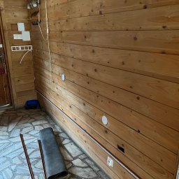 NKTelektrick - Drewniane wnętrze z instalacją elektryczną w trakcie montażu w Zakopanem. Widoczne kable w listwach przypodłogowych i puszki pod gniazdka na ścianie.