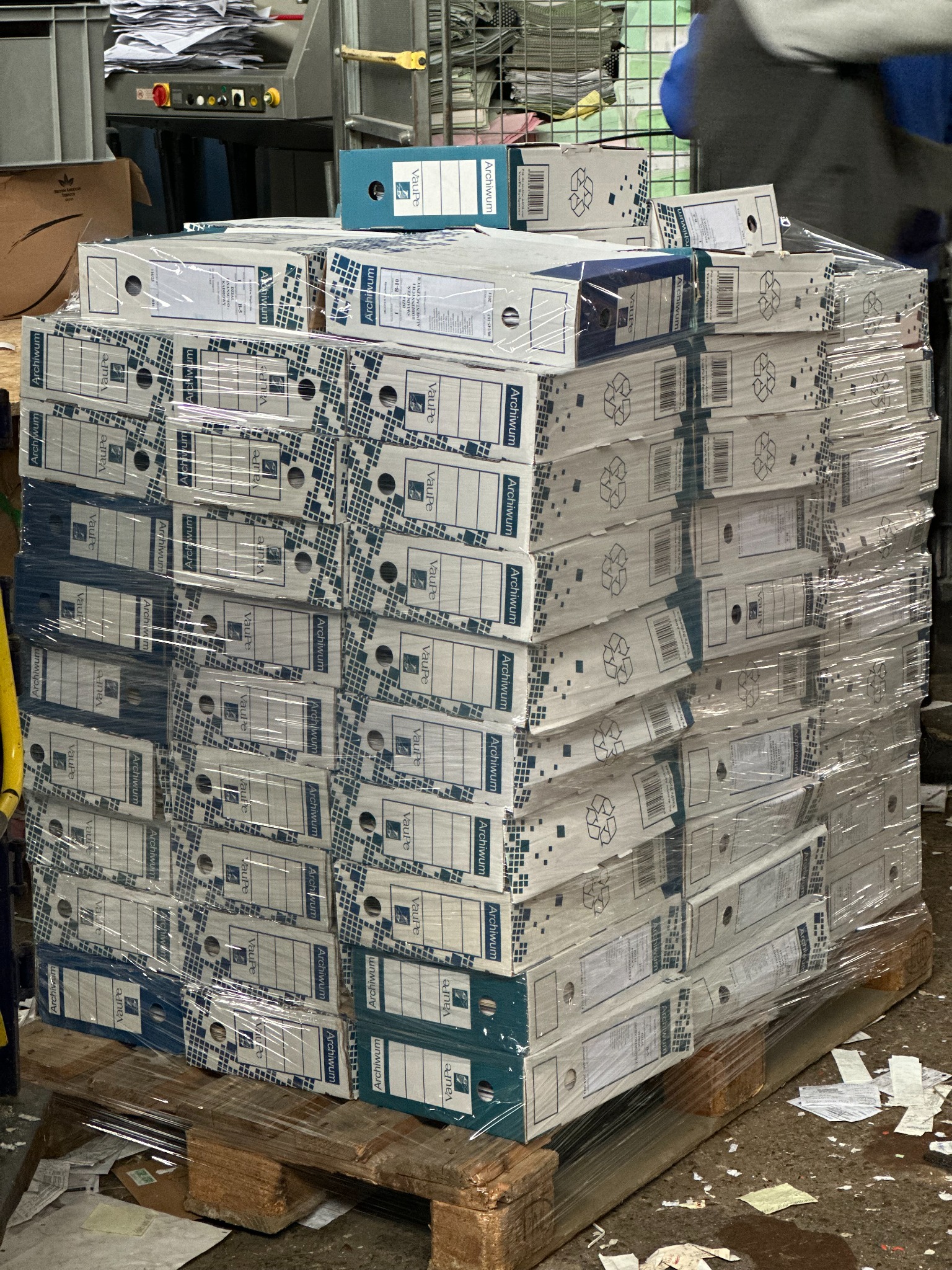 Stos segregatorów archiwizacyjnych marki Vaupe, owiniętych folią stretch na drewnianej palecie, gotowych do transportu lub składowania w magazynie.