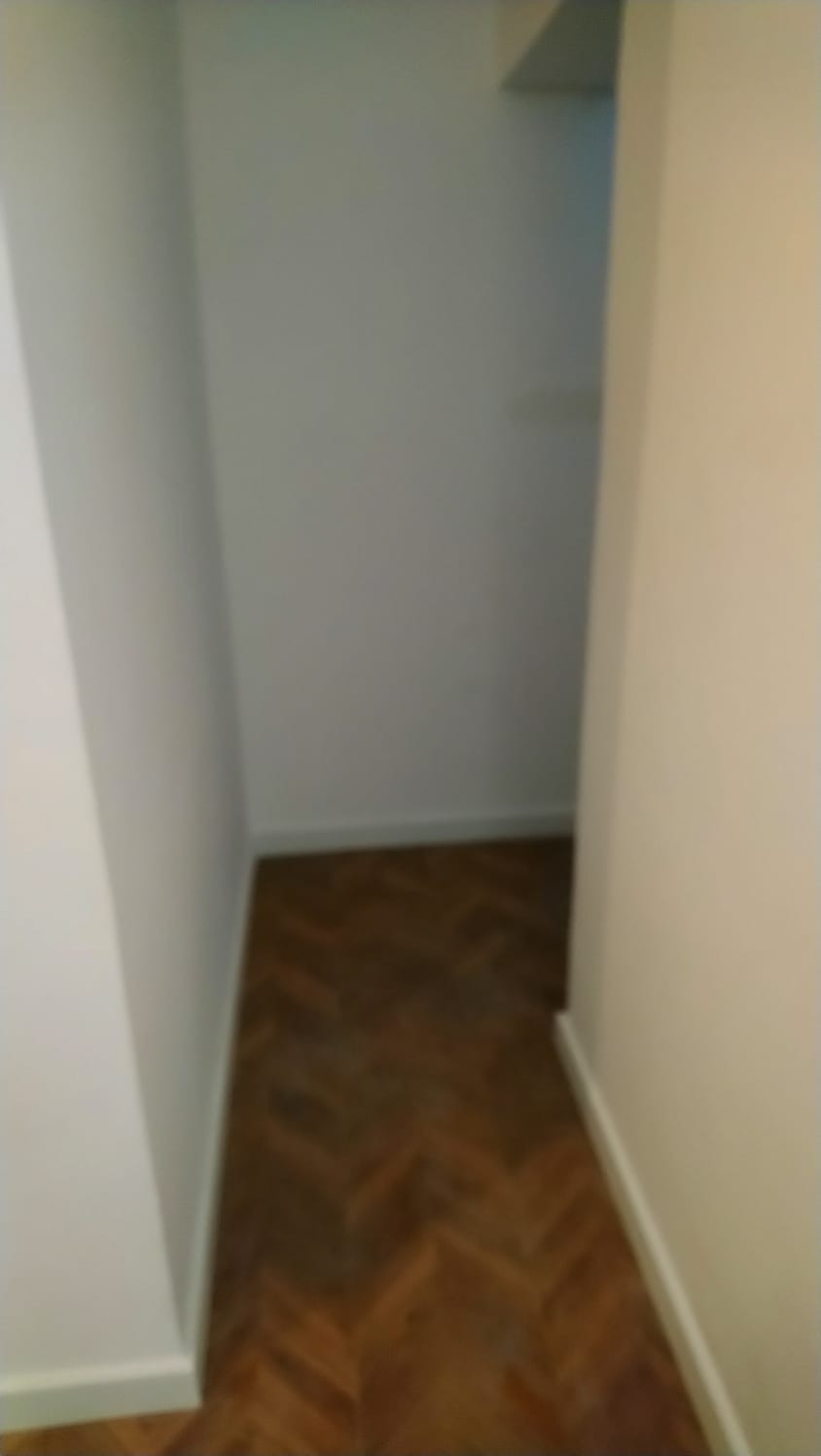 Wnętrze szafy wnękowej z parkietem w jodełkę, świeżo po malowaniu ścian na biało.