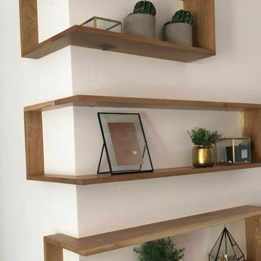 Drewniane półki ścienne w Słubicach, z dekoracjami: ramka ze zdjęciem, złota doniczka z rośliną i kaktusy w betonowych doniczkach.