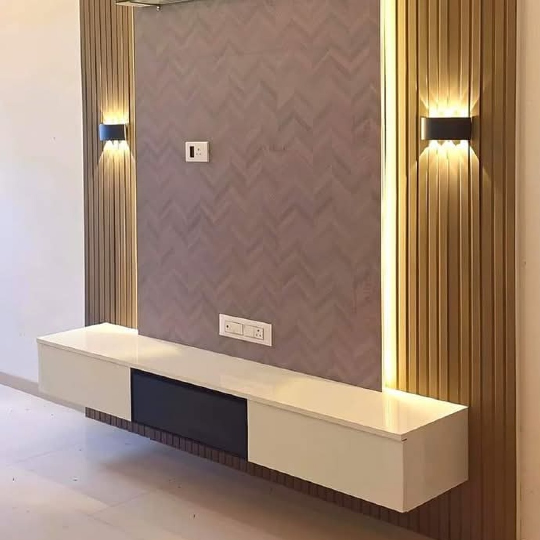 Nowoczesna ściana TV z podświetlanymi panelami drewnianymi po bokach, szarą tapetą w jodełkę i białą, wiszącą szafką RTV z czarnym elementem.