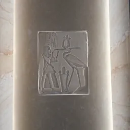 Płaskorzeźba z motywem starożytnego Egiptu, przedstawiająca postać ludzką i ptaka, umieszczona na kolumnie z podświetleniem LED, stanowiąca element dekoracyjny wnętrza.