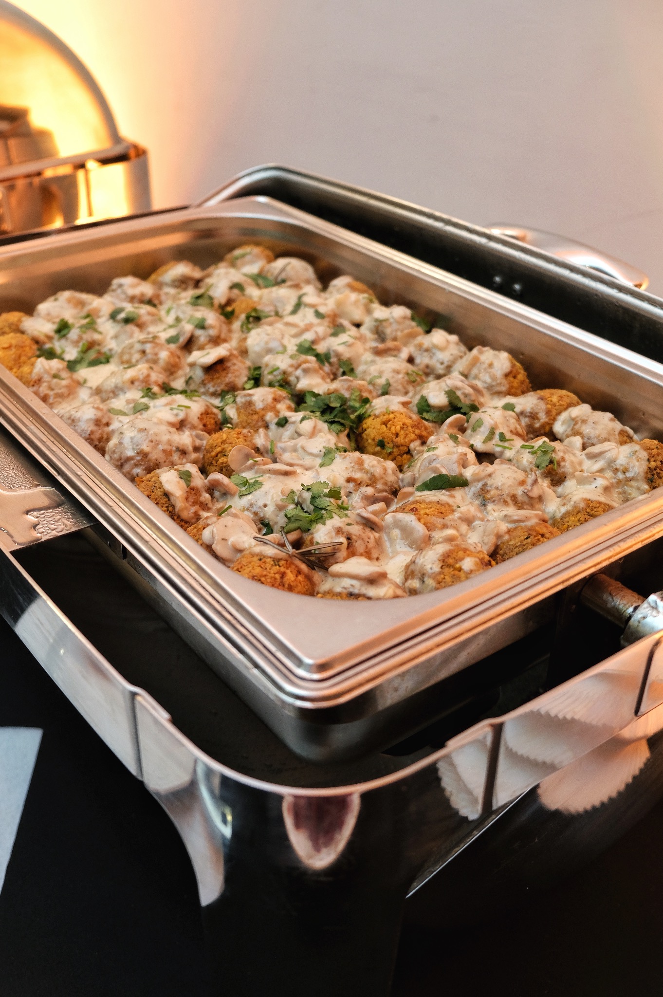 Metalowa bemar z falafelami w kremowym sosie grzybowym, posypanymi świeżą pietruszką, przygotowana przez firmę z Wrocławia.