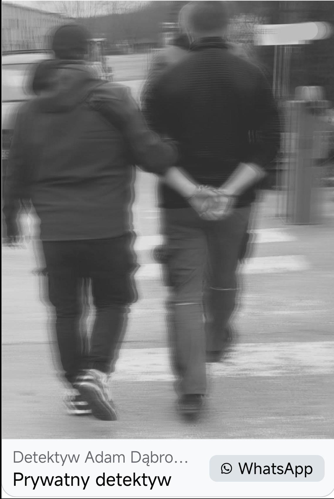 Rozmazane, czarno-białe zdjęcie dwóch osób idących po ulicy. Jedna z nich ma ręce skute kajdankami za plecami. Ujęcie z perspektywy osoby trzeciej.