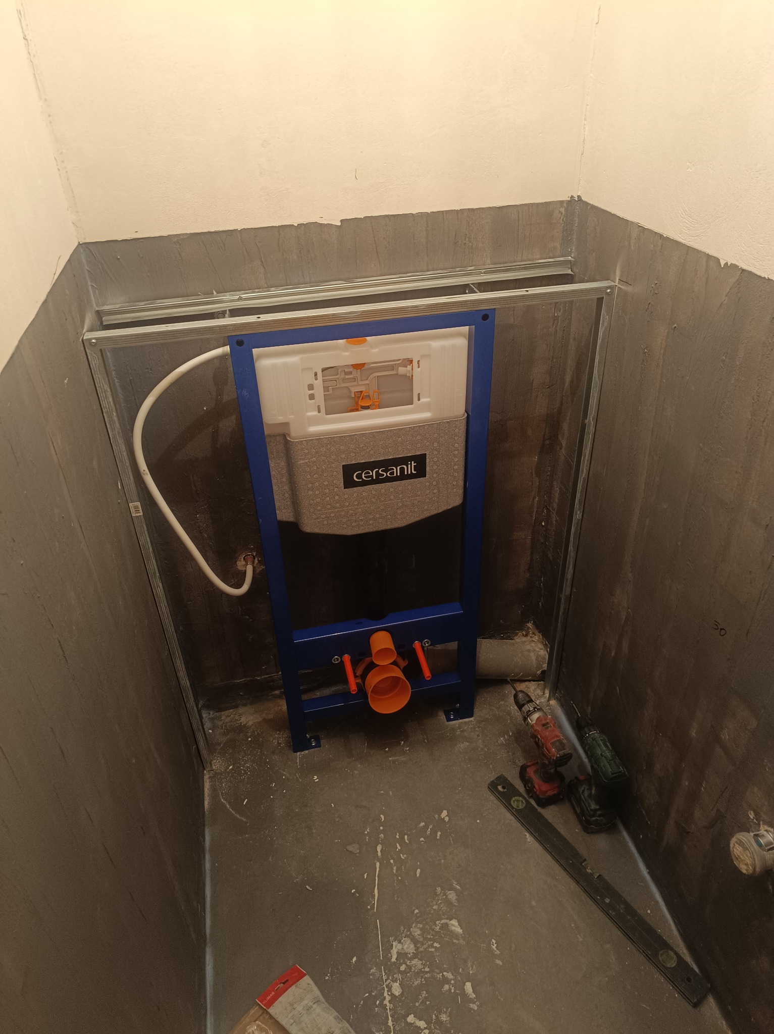 Stelaż podtynkowy Cersanit zamontowany w surowej łazience, widoczne narzędzia i fragment instalacji. Przygotowanie do montażu ceramiki sanitarnej.