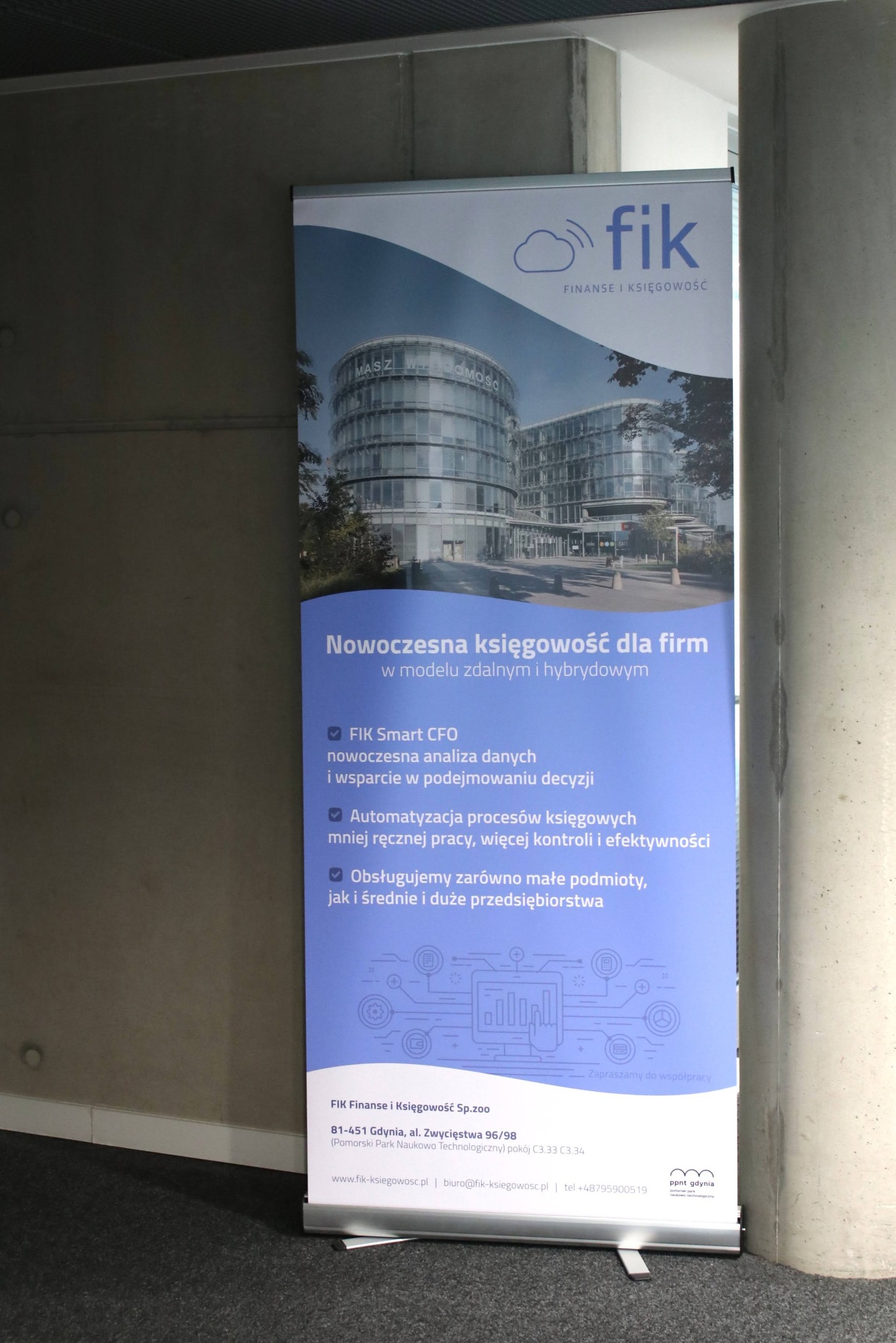 Roll-up reklamowy firmy księgowej FIK z Gdyni. Nowoczesne budynki w tle, hasło: Nowoczesna księgowość dla firm. Automatyzacja procesów, wsparcie w podejmowaniu decyzji.