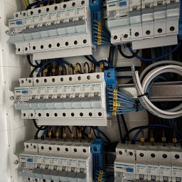 Siekierski Smart Elektryk - Rozdzielnica elektryczna Hager z zamontowanymi bezpiecznikami i podłączonymi przewodami. Widoczne oznaczenia na przewodach i elementach rozdzielnicy.