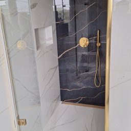 Promax ekskluzywne wnętrza - Nowoczesna kabina prysznicowa z czarnymi płytkami imitującymi marmur z złotymi żyłami i złotą armaturą, widok z boku, marmurowe płytki na podłodze i ścianach.