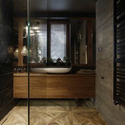 Anna Bartman - Z WNĘTRZA - Nowoczesna łazienka z czarnymi płytkami imitującymi łupek na ścianie prysznicowej, drewnianą szafką pod umywalką z dwiema białymi umywalkami nablatowymi, grzejnikiem drabinkowym w kolorze...