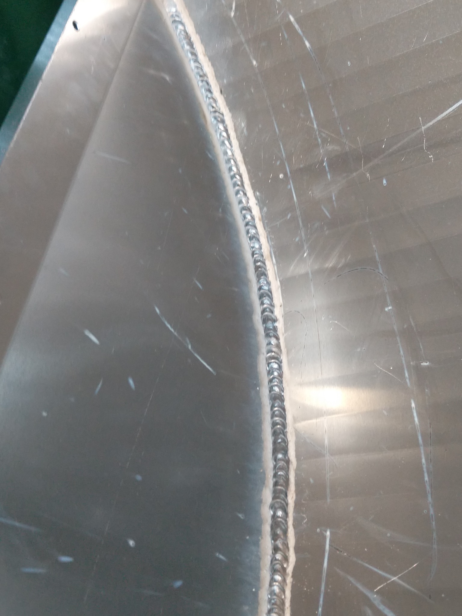 Detal spoiny na metalowej powierzchni z widocznymi śladami szlifowania i rysami.