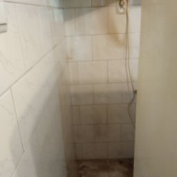 Firma Sprzątająca Blask - Zanieczyszczona, wykafelkowana wnęka z widocznym gniazdkiem elektrycznym i wiszącym kablem, wymagająca gruntownego wysprzątania w Gorzowie Wielkopolskim.