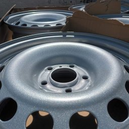 Firma usługowa Kacper Juskowiak - Świeżo pomalowane na srebrno felgi samochodowe w kartonowym opakowaniu, widoczne otwory montażowe i wentylacyjne.