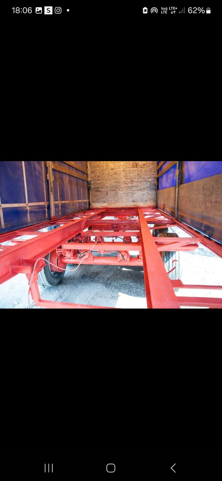 Wnętrze naczepy z widoczną czerwoną, pomalowaną ramą podwozia i kołem. Widok z tyłu naczepy.