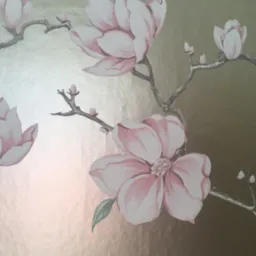 Delikatny wzór tapety z motywem magnolii w odcieniach różu i bieli na metalicznym, złotym tle.