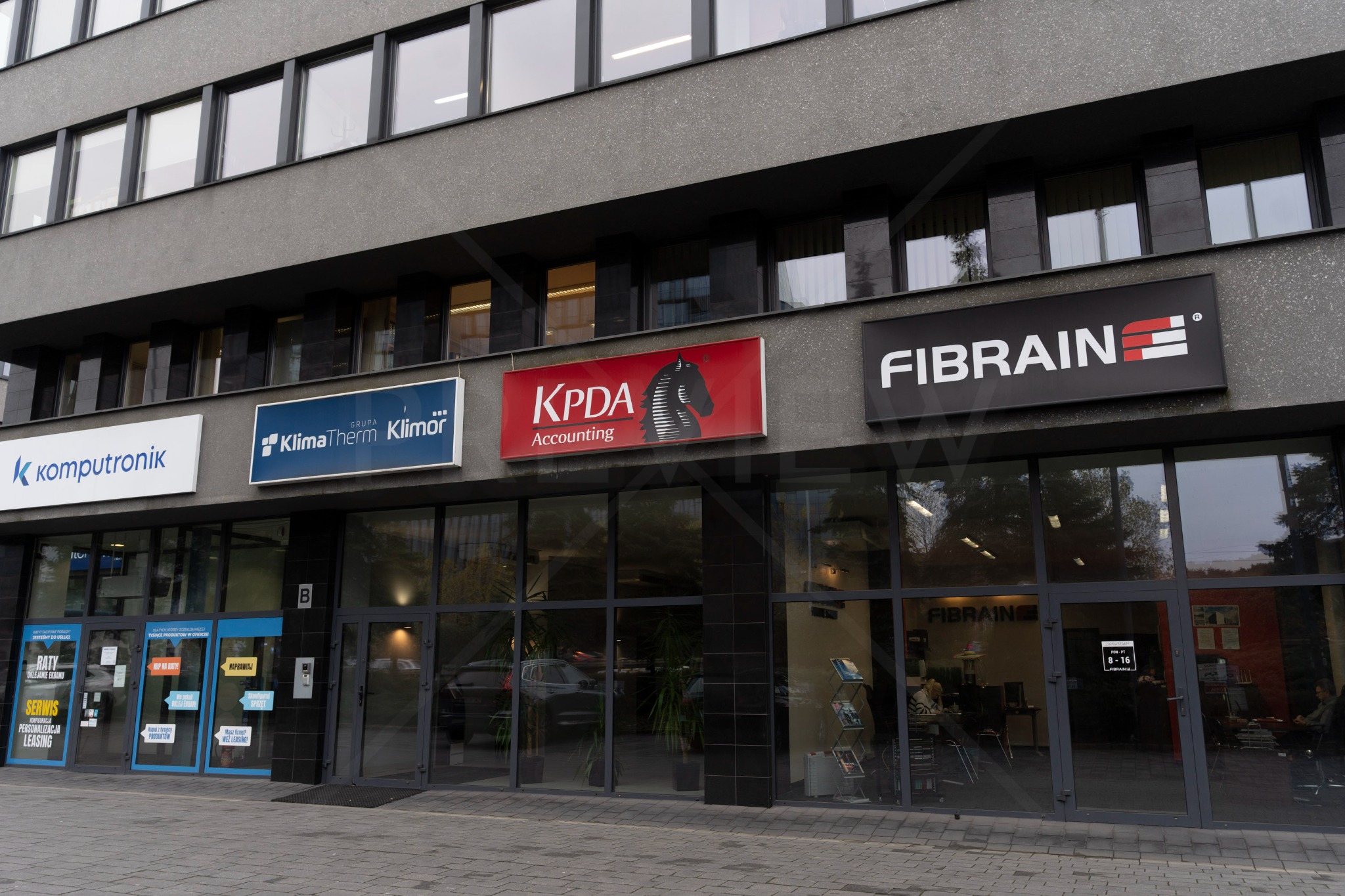 Fasada biurowca w Katowicach z szyldami firm, w tym KPDA Accounting z logo konika szachowego, oferującej usługi księgowe i doradztwo podatkowe.