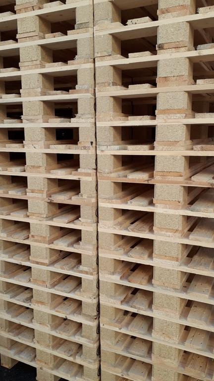 Stos jasnych, drewnianych palet euro ułożonych jeden na drugim, widok z bliska na strukturę drewna i przestrzenie między deskami.