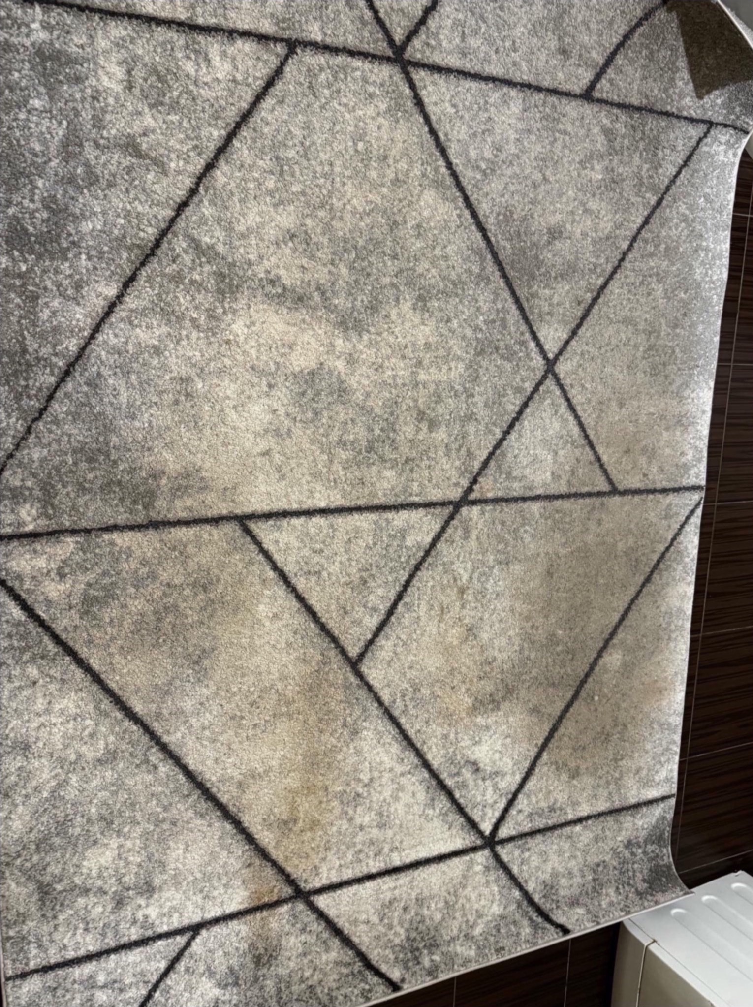 Szary dywan z geometrycznym wzorem linii, widoczne plamy przed czyszczeniem, realizacja w Łomiankach.