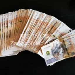 Plik banknotów 200 zł ułożonych wachlarzowo na ciemnym, drewnianym blacie, widoczne numery seryjne i fragmenty portretu króla Zygmunta I Starego.