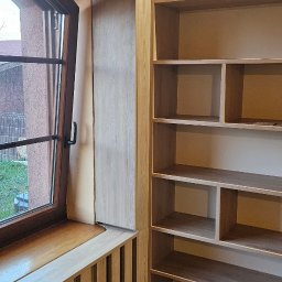 Bomax - Jasna, drewniana zabudowa wnęki okiennej z grzejnikiem i regałem z oświetleniem LED w górnej części.