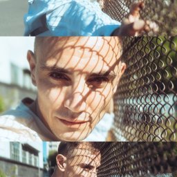 Mustache Lens Media - Portret młodego mężczyzny opierającego się o metalową siatkę, z cieniem siatki na twarzy, w tle budynki i ulica.