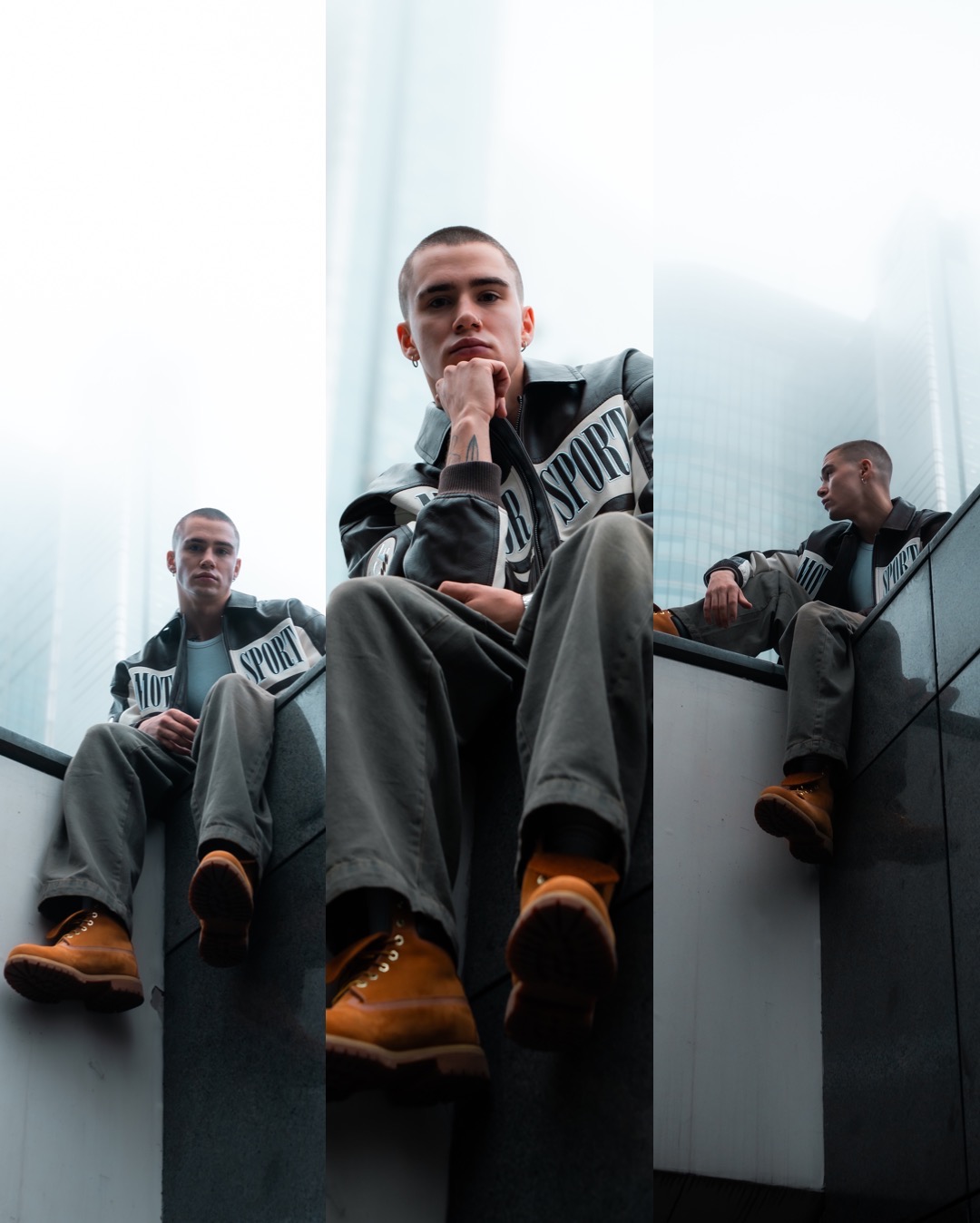 Młody mężczyzna w skórzanej kurtce z napisem 'SPORT' siedzący na krawędzi budynku na tle szklanych biurowców, ujęcie z dołu.