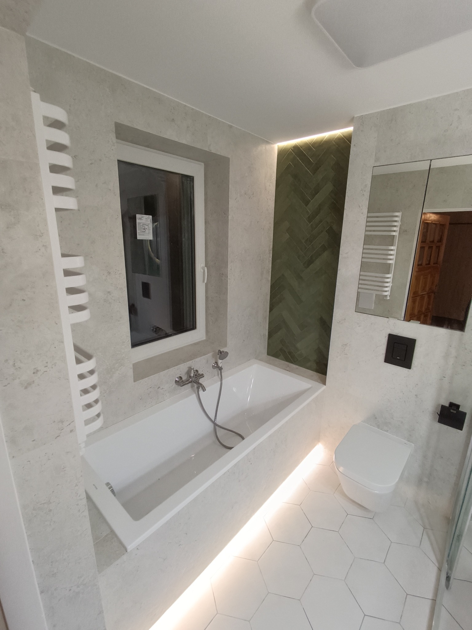 Nowoczesna łazienka w Piątkowisku z wanną w zabudowie, podświetleniem LED, heksagonalną podłogą i ścianą z zielonej cegiełki ułożonej w jodełkę.