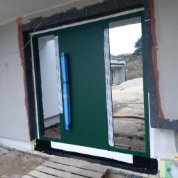 Drzwi aluminiowe panelowe, kolor zielony, widoczne warstwy montażowe i ich usczelnienie