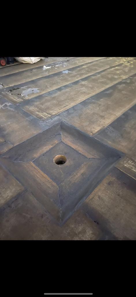 Szara powierzchnia dachu z wzorem rombów i otworem w centralnym rombie, widoczne ślady wilgoci.