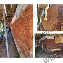 Wisebud - Budowa ściany z czerwonej cegły na zewnątrz budynku, widoczne rusztowania i narzędzia murarskie.