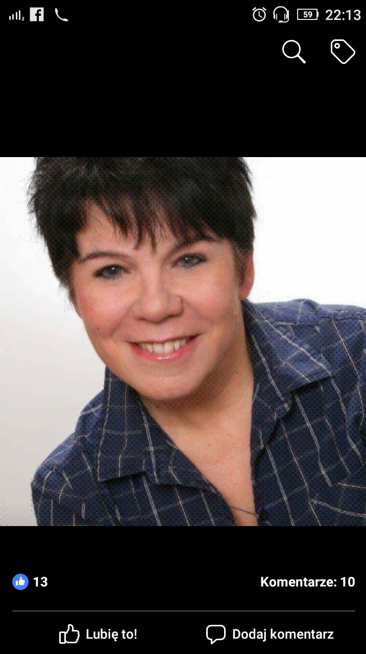 Portret uśmiechniętej kobiety w niebieskiej koszuli w kratę z krótkimi ciemnymi włosami, zrzut ekranu z Facebooka.