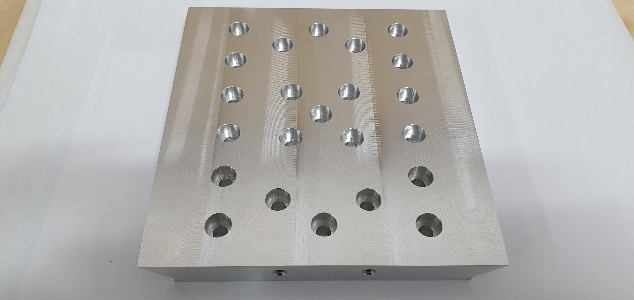 Aluminiowa płyta z równomiernie rozmieszczonymi otworami, widoczne ślady obróbki skrawaniem na powierzchni.